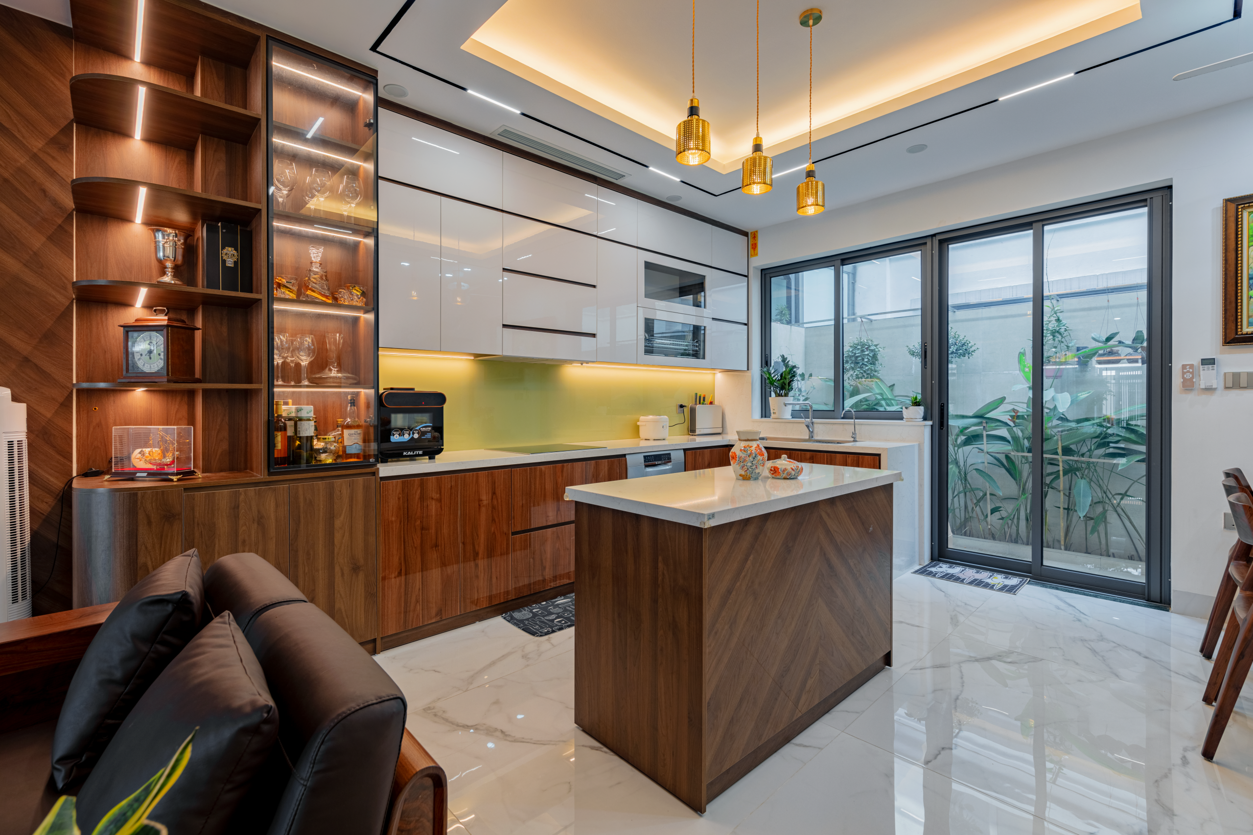 Hệ tủ bếp trên sử dụng cánh acrylic trắng bóng tương phản với hệ tủ dưới và đảo bếp ốp gỗ